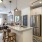 Spacious and well lit kitchen with wood floors and stainless steel appliances. 
