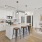 Spacious and well lit kitchen with wood floors and stainless steel appliances. 