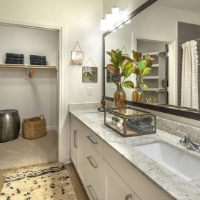 bathroom Large well lit bathroom with large mirror and white cabinets with a spacious walk in closet.