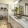 Large well lit bathroom with large mirror and white cabinets with a spacious walk in closet.